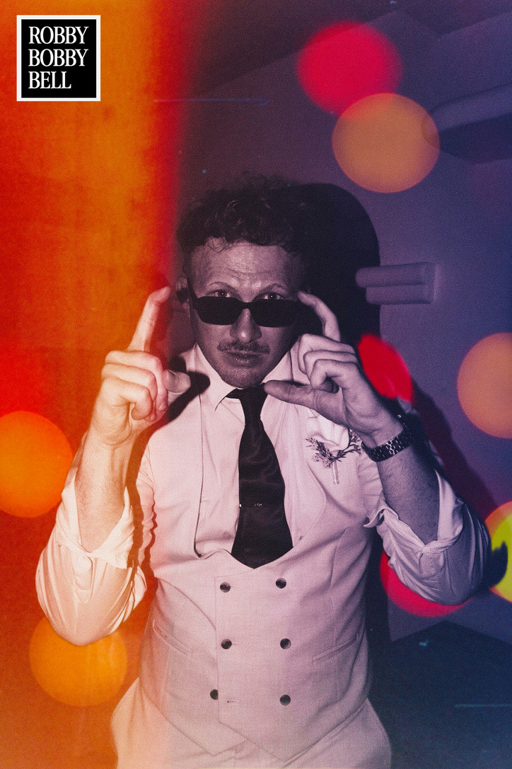 A wedding guest in sunglasses caught in colourful light leaks
